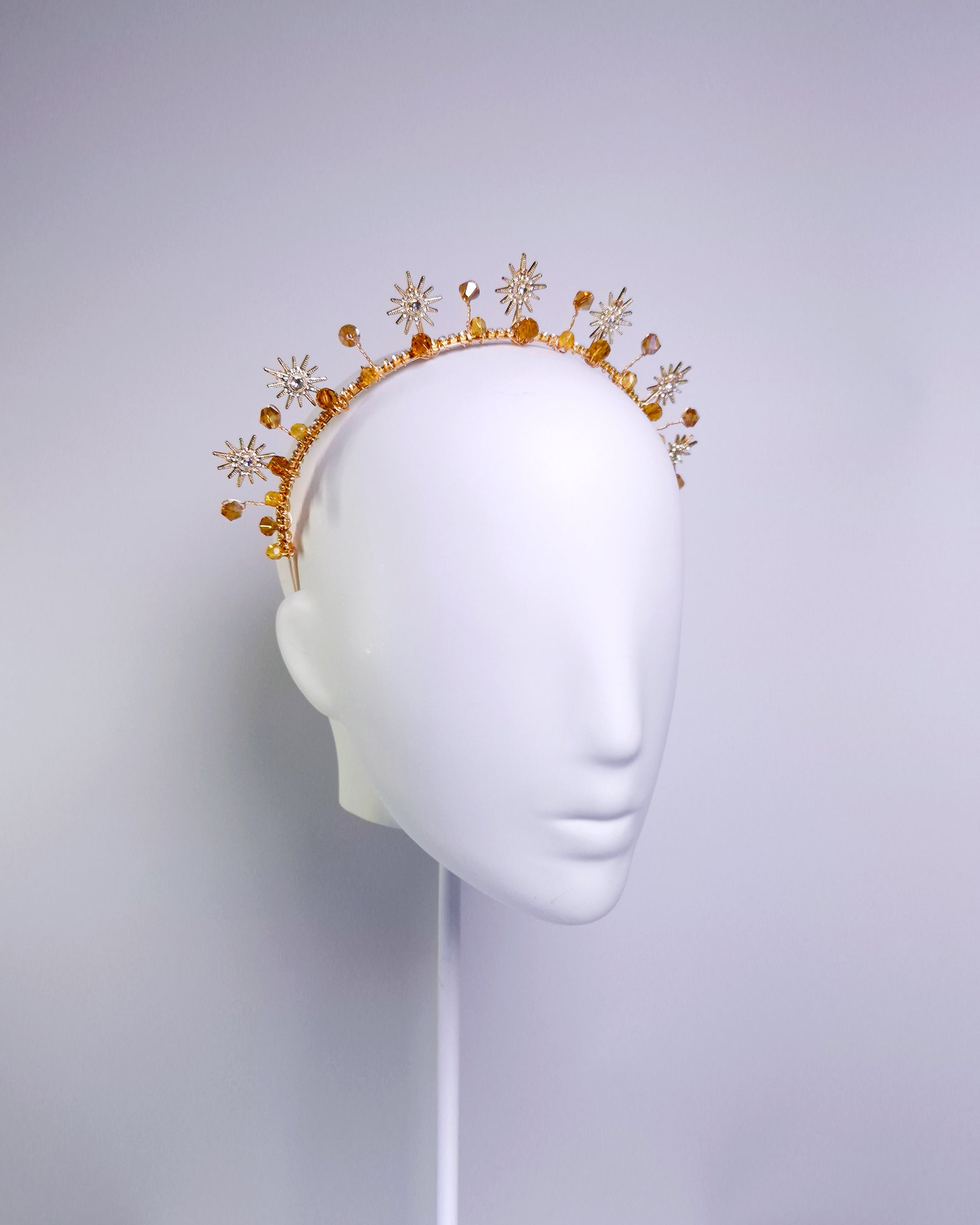 Decorative headband with gold and orange elements on a mannequin head against a white background